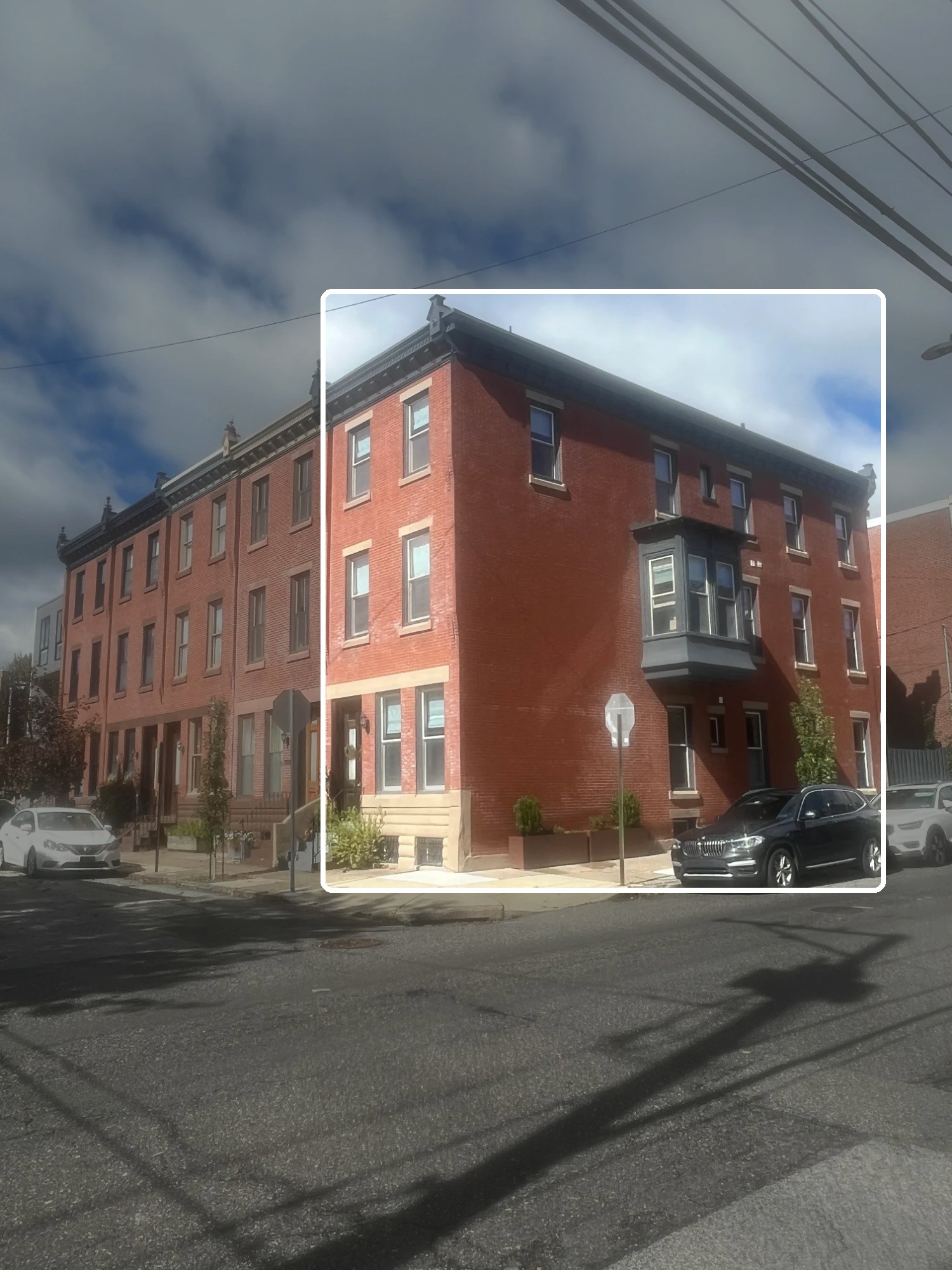Red brick three-story multifamily rowhouse on a Philadelphia corner, with one building outlined