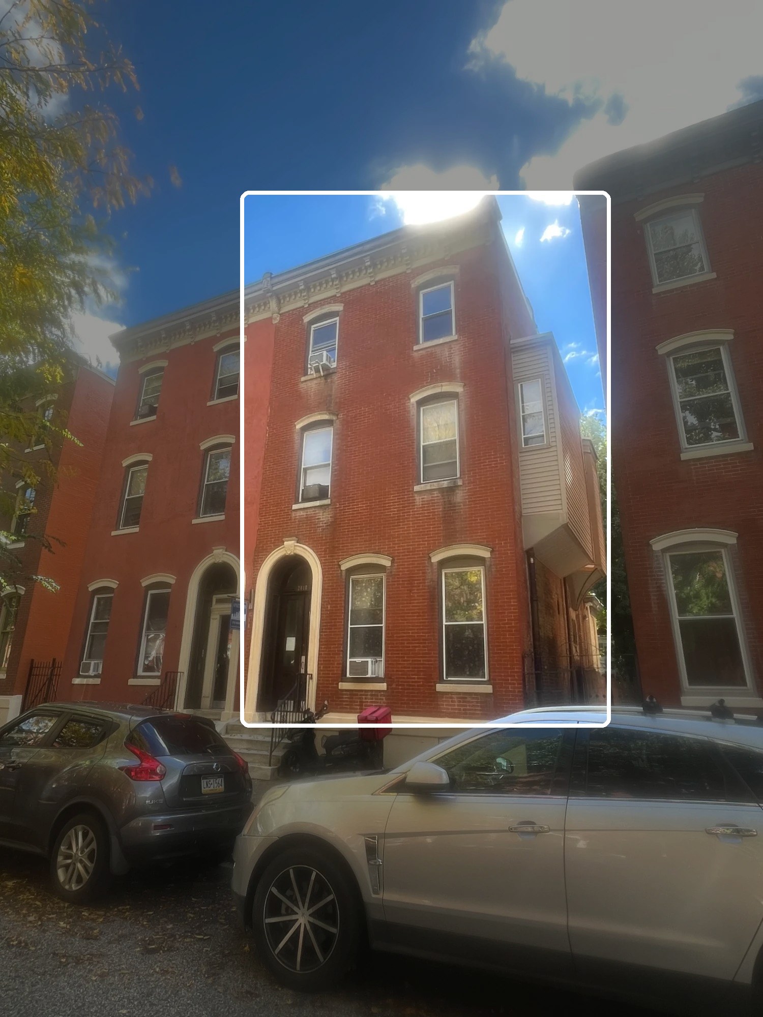 Three-story brick multifamily building on a Philadelphia street, with one building outlined