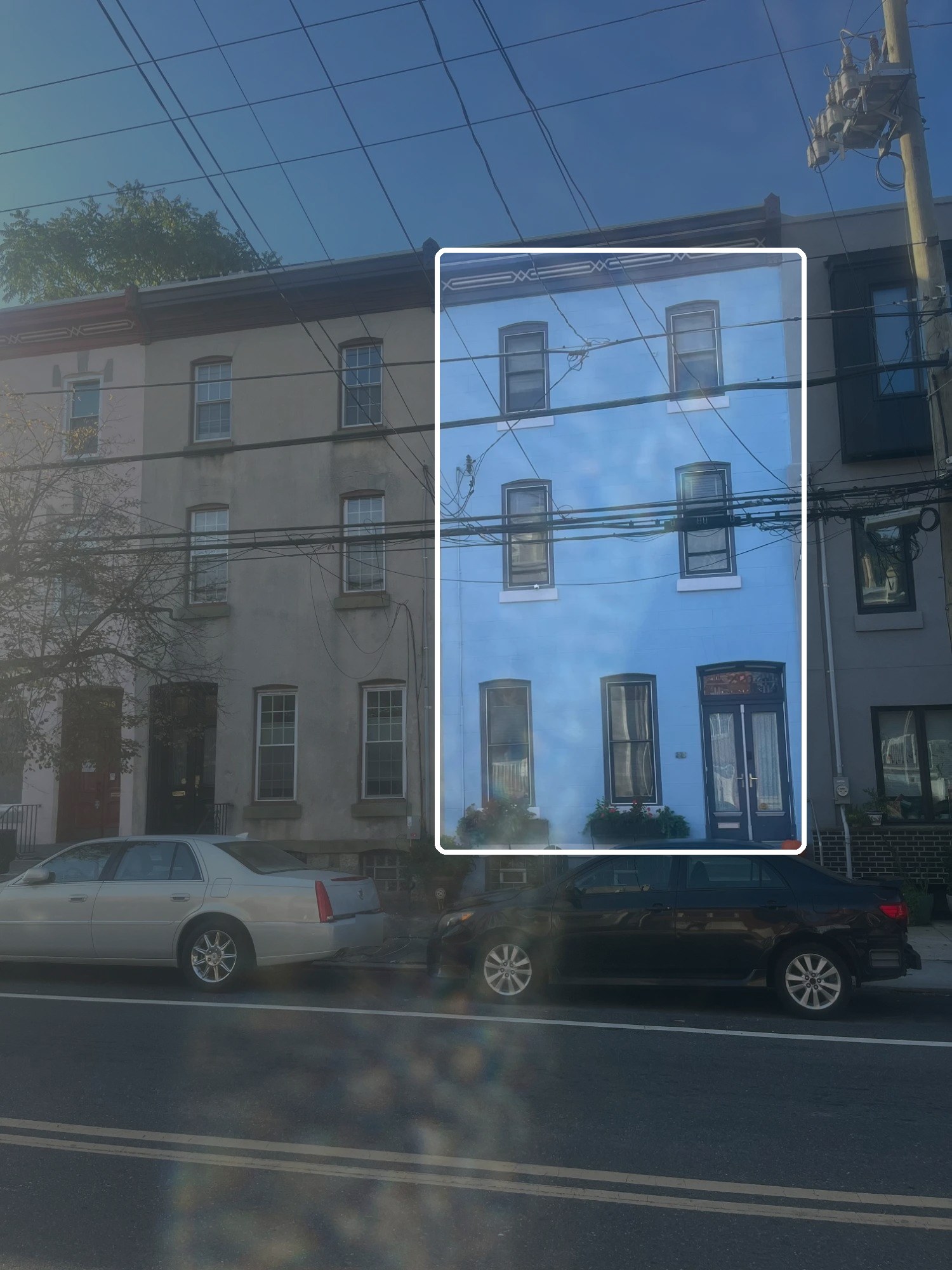 Three-story rowhouses on a Philadelphia street, with one building outlined